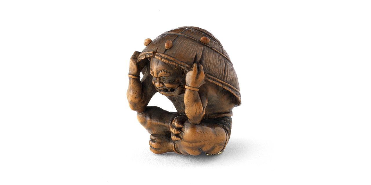 Netsuke / Oni se protégeant sous un chapeau d’une pluie de pois lors de la fête du Setsubun où l’on chasse les démons, Japon, XIX^e siècle. © © musée des Tissus – Pierre Verrier